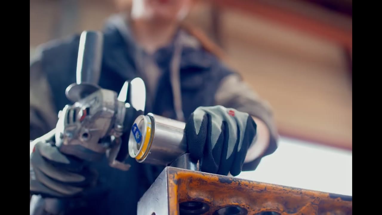 Standbild einer Modeproduktion: eine Designerin bearbeitet recycelte Red-Bull-Dosen mit einem Werkzeug