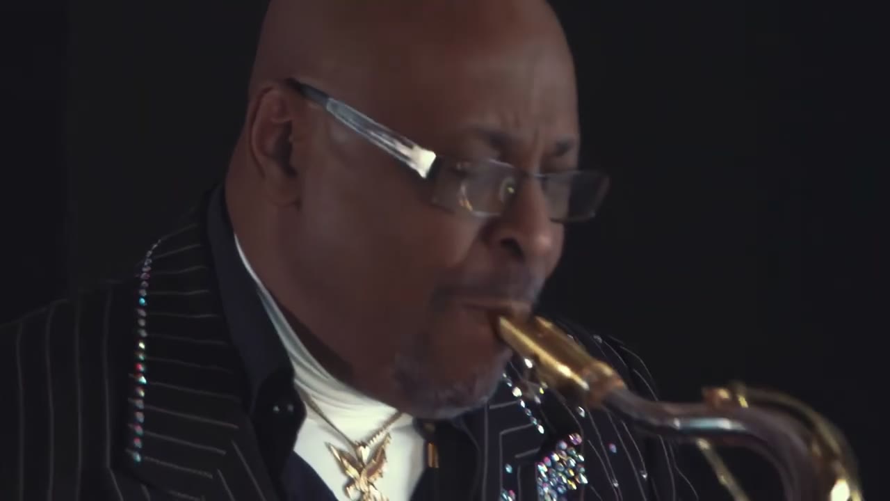Saxophonist mit Brille und Nadelstreifenanzug spielt in einem dunklen Studio