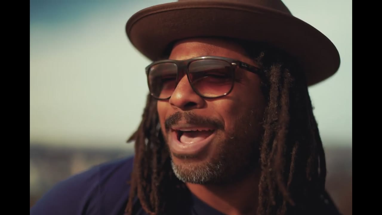 Roger William Smith mit Hut und Sonnenbrille singt im Freien im Musikvideo Little Rock, Little Roll