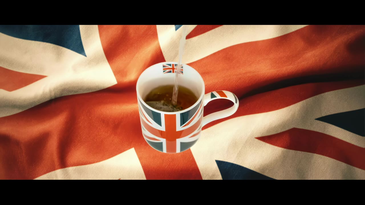 Milch wird in eine Union-Jack-Tasse mit Tee gegossen, auf einer britischen Flagge