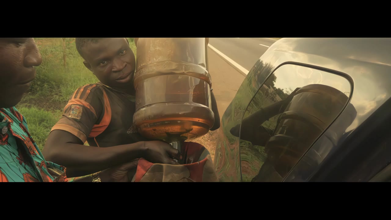 Trailer zu Dying to Clothe You: ein Bauer gießt Flüssigkeit aus einem Behälter in Westafrika